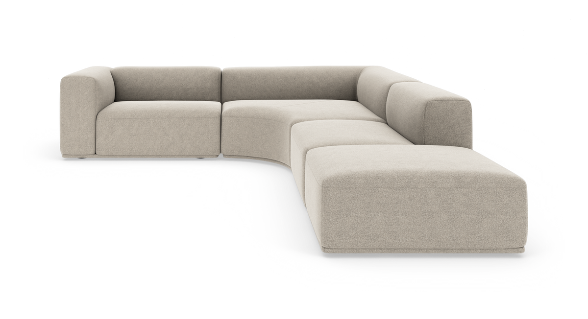 Modulær hjørnesofa i beige stof med afrundede former, lav ryg og brede armlæn, frilagt på hvid baggrund.