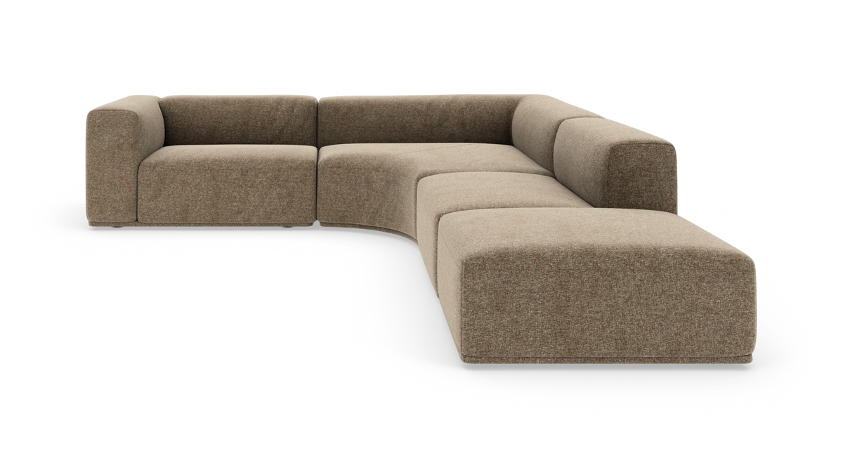 Modulær L-sofa i beige stof med afrundet midtersektion og lave, bløde former, frilagt på hvid baggrund.