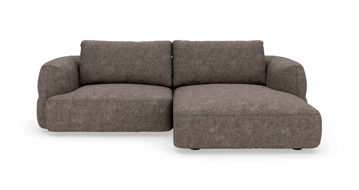 Brungrå modulsofa med højre chaiselong, bløde afrundede armlæn og stofbetræk, frilagt mod hvid baggrund.