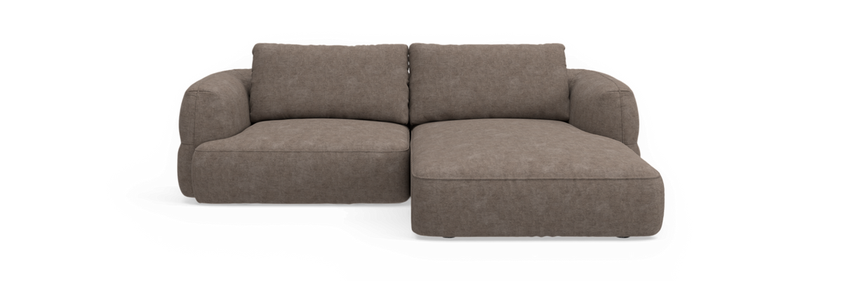 Brungrå modulsofa med chaiselong til højre, afrundede armlæn og tykke hynder, frilagt på sort baggrund.